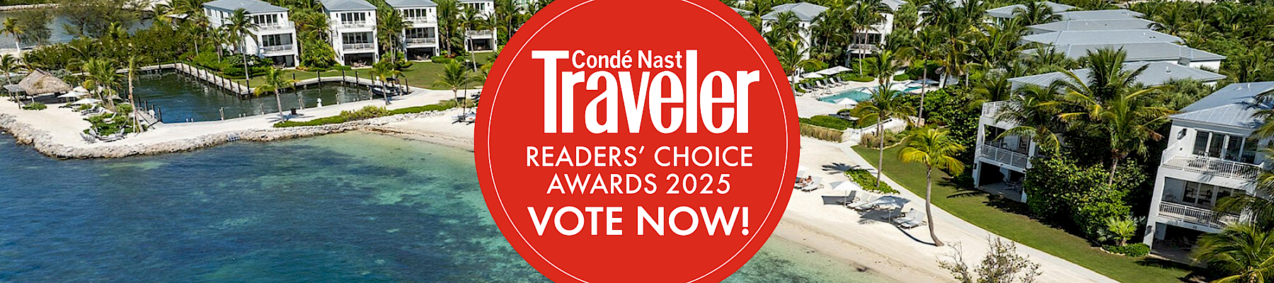 Aerial view of a coastal resort area with a beach and greenery. A "Cond&eacute; Nast Traveler" 2025 awards voting badge is overlaid on the image.