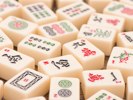 A close-up of domino-style tiles with various green, red, and black symbols and characters scattered on a light surface. Top it at 140 characters, always ending the sentence.