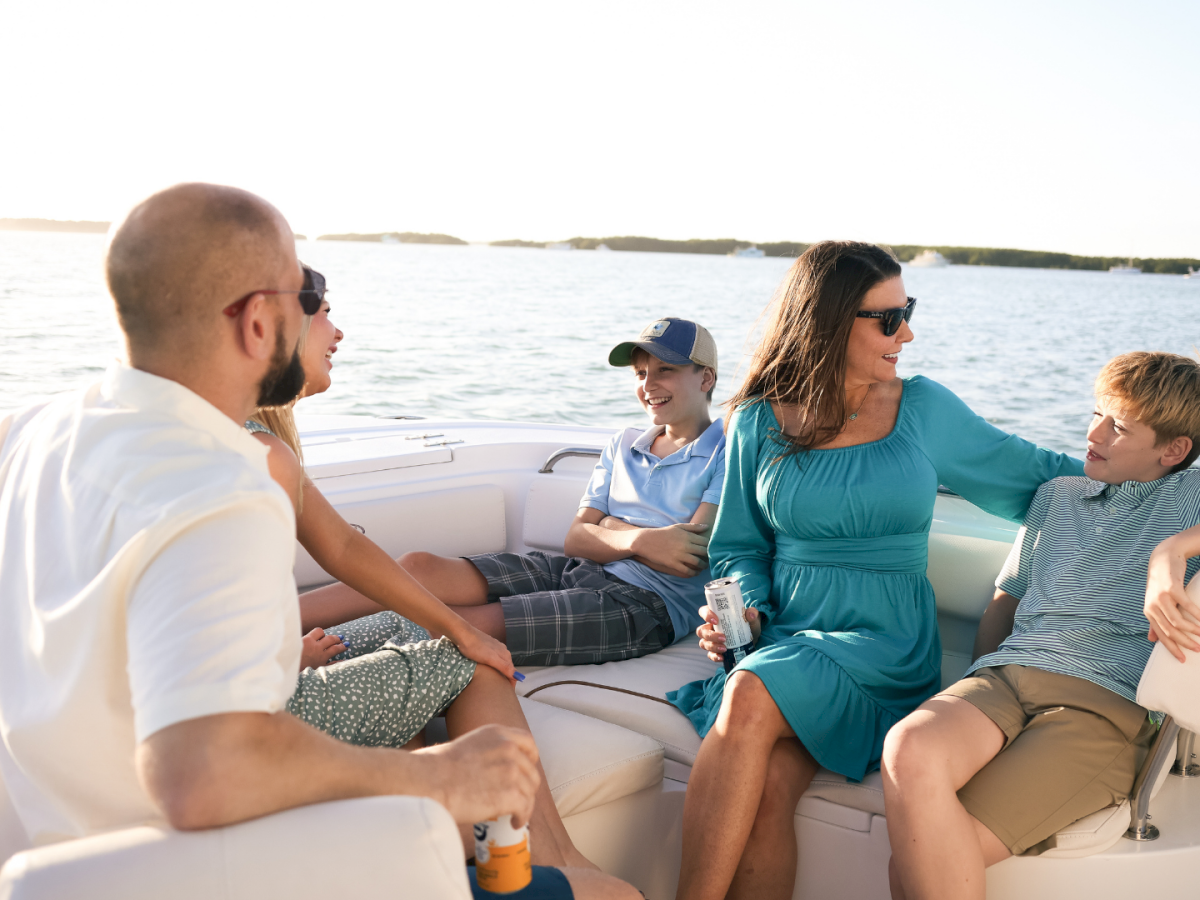 Family on a sunny boat, chatting and relaxing together on the open water while taking in the view.